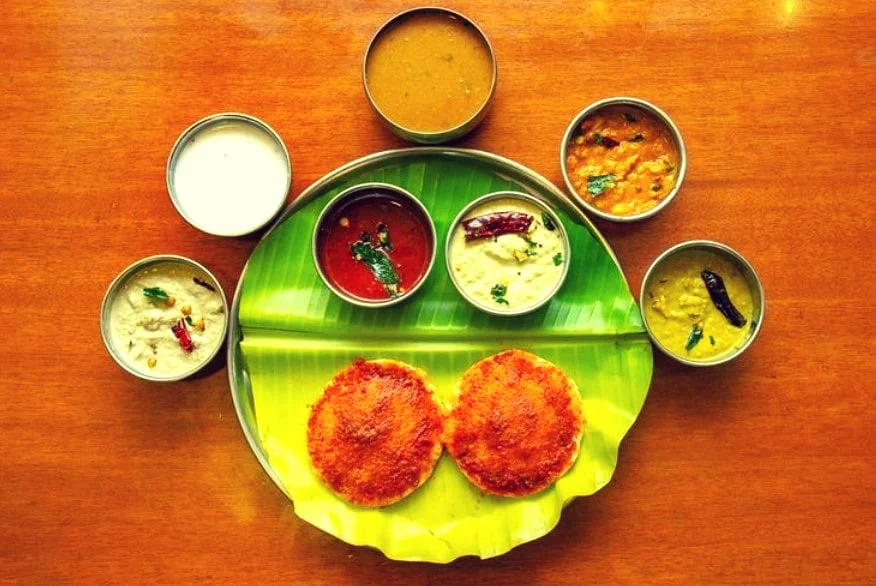 Image of a variety of South Indian food dishes served on plates at Chutneys restaurant in Hyderabad, India. The dishes include idli, dosa, vada, chutney, and sambar.