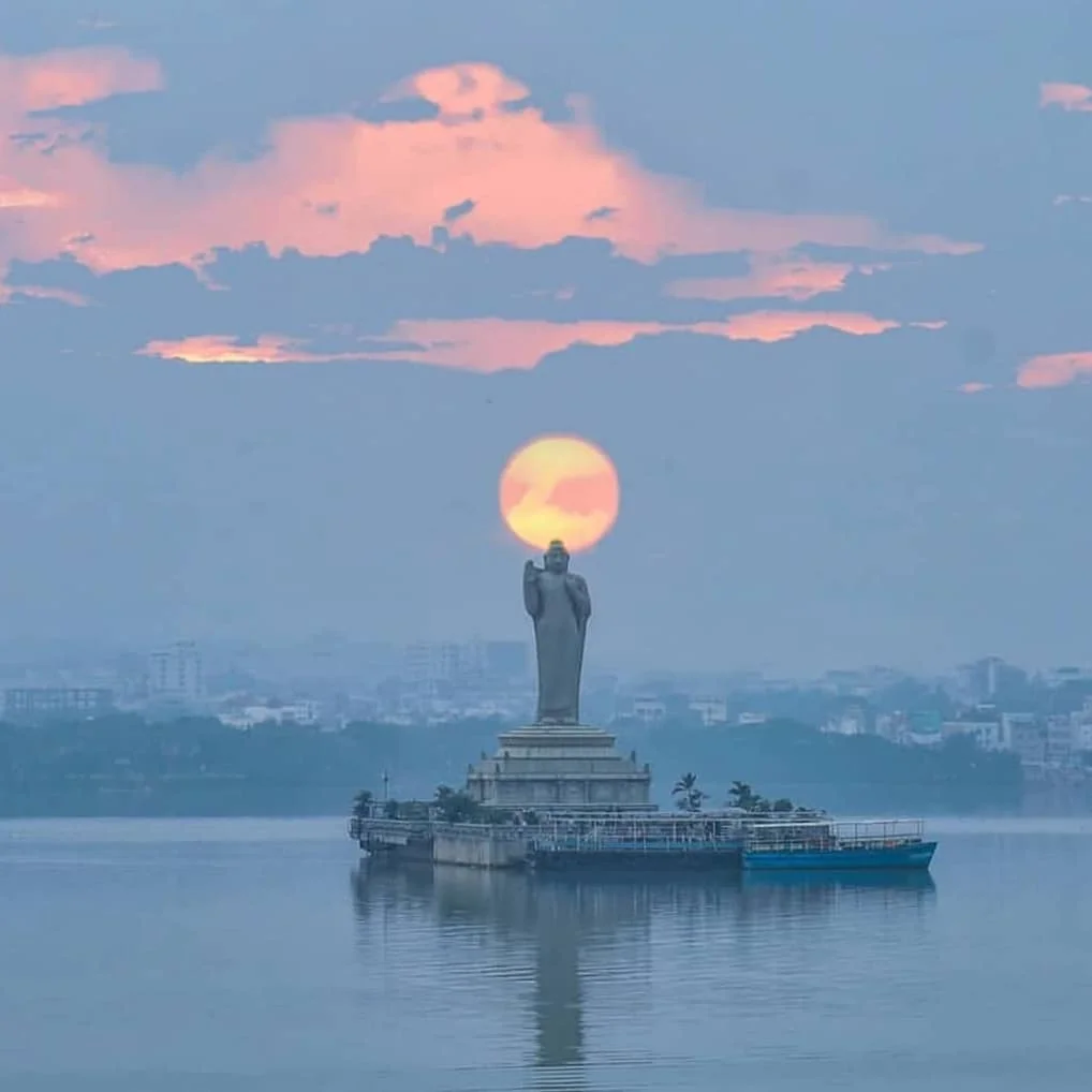 Hussain Sagar Lake in Hyderabad, India - a large man-made lake with a statue of Buddha in the center, surrounded by trees and a cityscape.